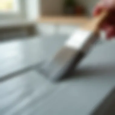 Close-up of a brush applying grey paint to wood